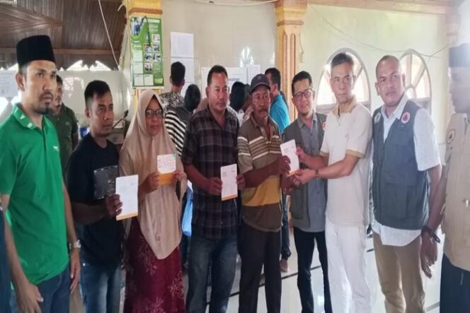 
					Plt Kalaksa BPBD Aceh Utara, Fauzan, menyerahkan bantuan dana rehab rumah secara simbolis kepada warga di Kecamatan Sawang (Dok. Jubir Pemkab Aceh Utara).